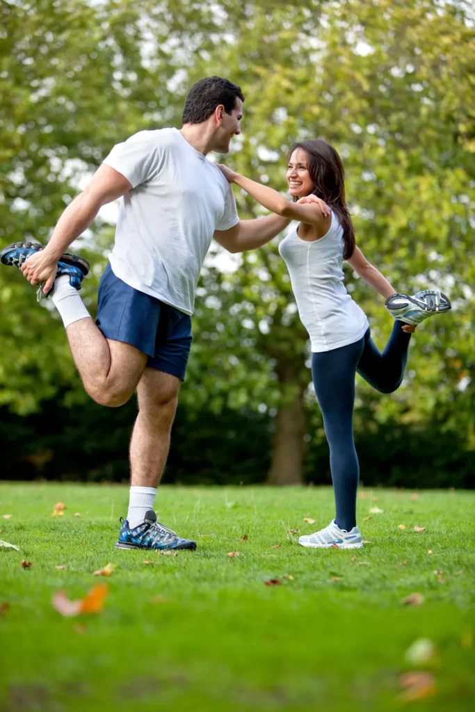 man and woman stretching legs in the park utc
